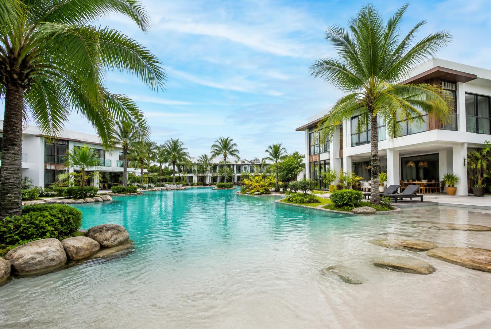 Montaire Parañaque vacation rental with lagoon-style wave pool, white modern villa architecture, and tropical palm landscaping